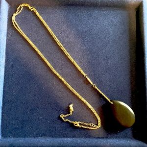 Long gold necklace with large black pendant